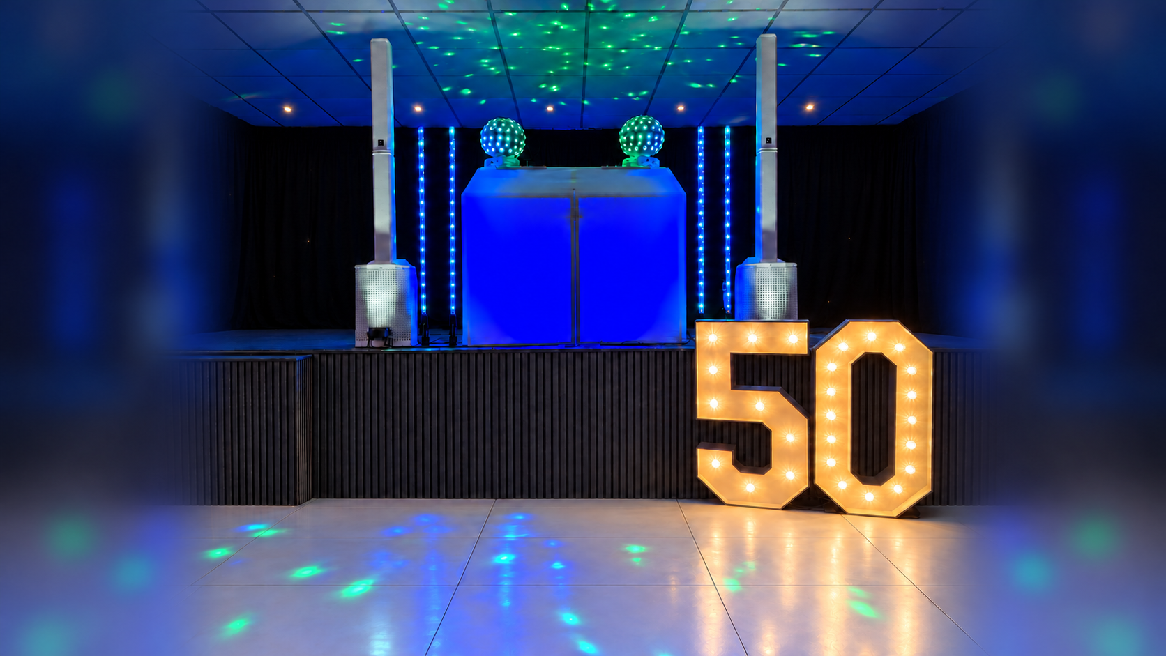 Dave’s Signature Set Up with white column speakers, blue DJ booth and colourful disco lighting, with softly blurred side fill
